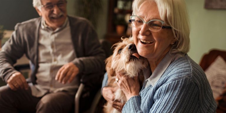Senior couple with dog licking woman's cheek